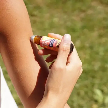 Persona aplicando roll-on calmante natural para picaduras de mosquito y plantas con efecto refrescante y alivio inmediato