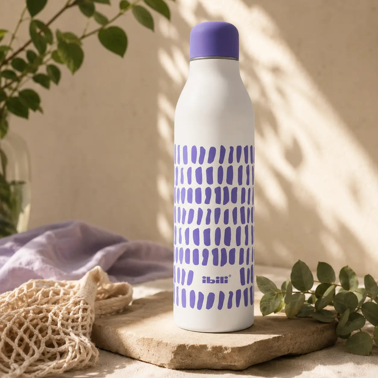 Botella térmica reutilizable IBILI de 500 ml fabricada en acero inoxidable con diseño blanco y lila sobre superficie natural